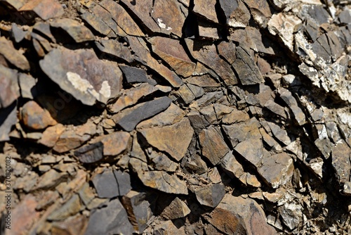 Cracked brown rock. Brown stones with sharp corners and fine gravel. Plates of red, black and brown stone. Stone ready for mining.