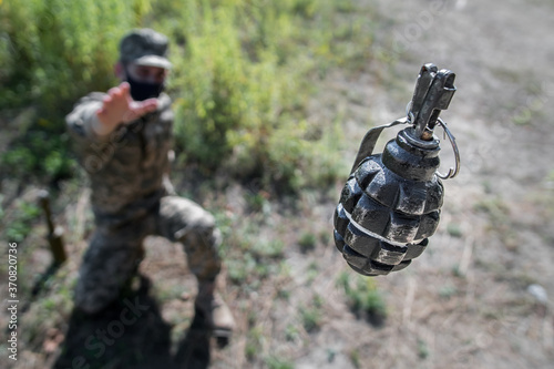 Grenade in flight with safety pin. A soldier in a mask threw a grenade, top view, focus on the grenade. F1 grenade in flight.