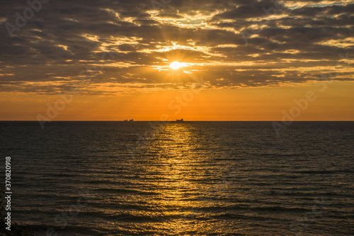 Golden sunrise at the sea on a cloudy morning. Ships can be seen against the background of sunrise on the horizon. Black sea. Sanzhiika. Ukraine