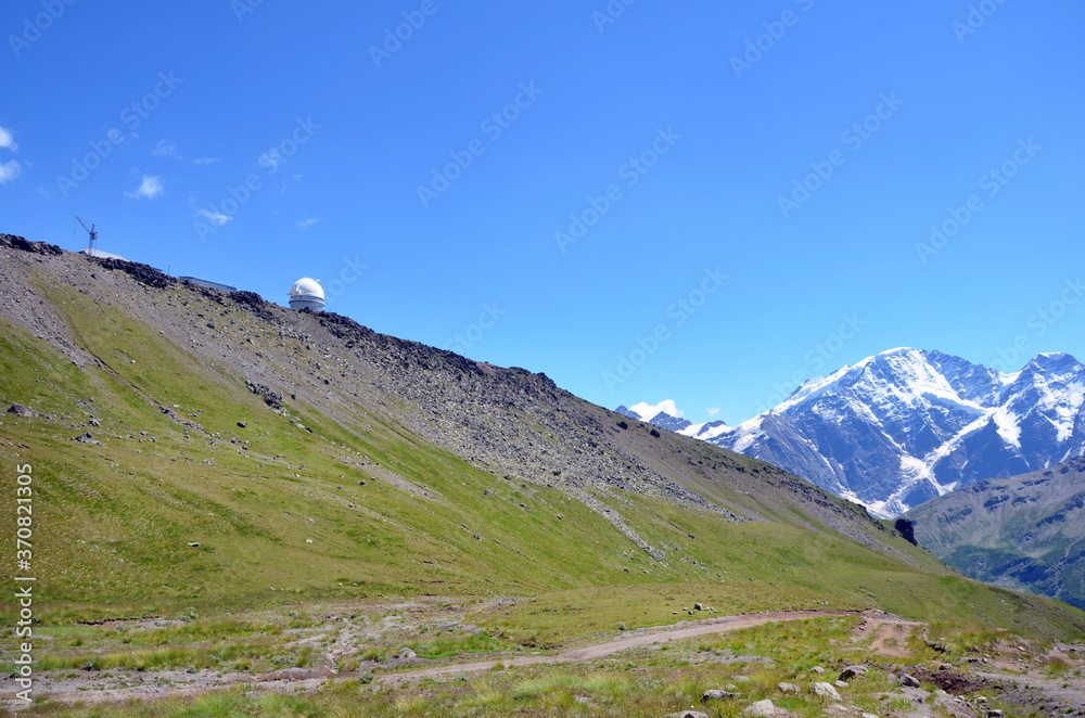 Beautiful landscape of the Caucasian mountains, nature of the Elbrus region. View of the green mountains of the Caucasus in August with snow-capped peaks in background. Wildlife of the Caucasus