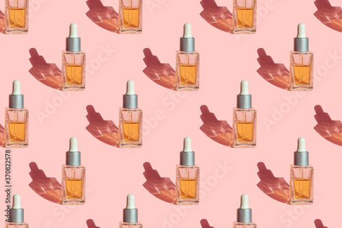 Seamless pattern of glass bottle with organic natural seed oil extract cosmetics for skin and hair care on pastel pink background.