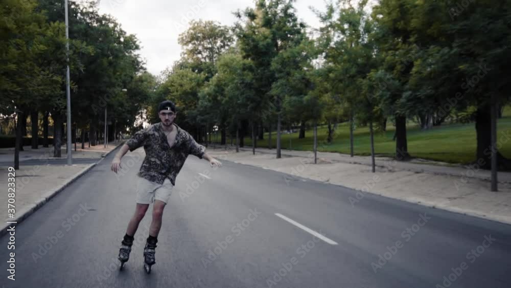 Plano medio retrato chico moderno caucasico con gafas, gorra negra y camisa colorida moderno con patinando libre libertad hipster estilo en el bosque luz y sombras sonriendo Plano medio retrato chico moderno caucasico con gafas, gorra negra y camisa colorida moderno con patinando libre libertad hipster estilo en el bosque luz y sombras sonriendo