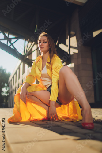Displaying fashion tendencies. Dark-haired attractive woman posturing in bright yellow fluffy cloak. photo
