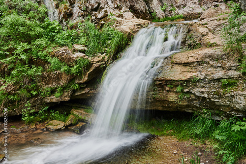 view of a small mountain river waterfall among large cobblestones from a cliff. photo