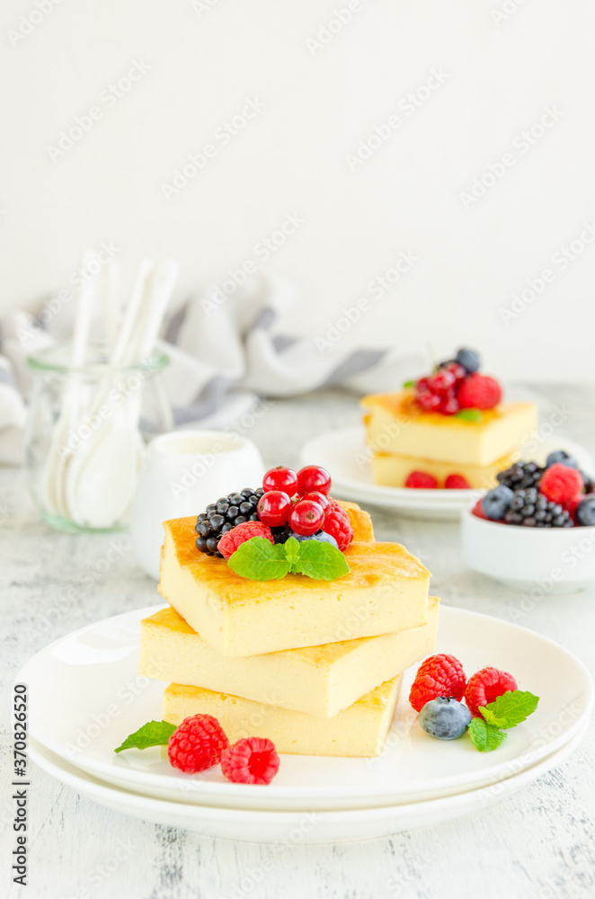 Homemade cottage cheese casserole with fresh berries and mint on top on a white plate. Healthy breakfast. Vertical, copy space.