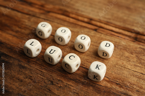 Cubes with phrase GOOD LUCK on wooden table  closeup