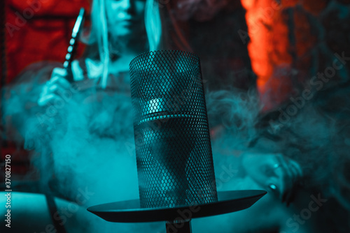 Girl smokes a hookah in blue neon lighting