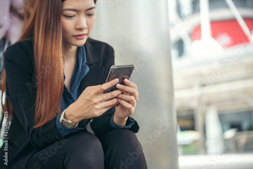 Asian Thai girl using mobile phone in business market.Person front view of Young Woman holding smartphone via internet to sending message and searching on digital device.Technology Concept.