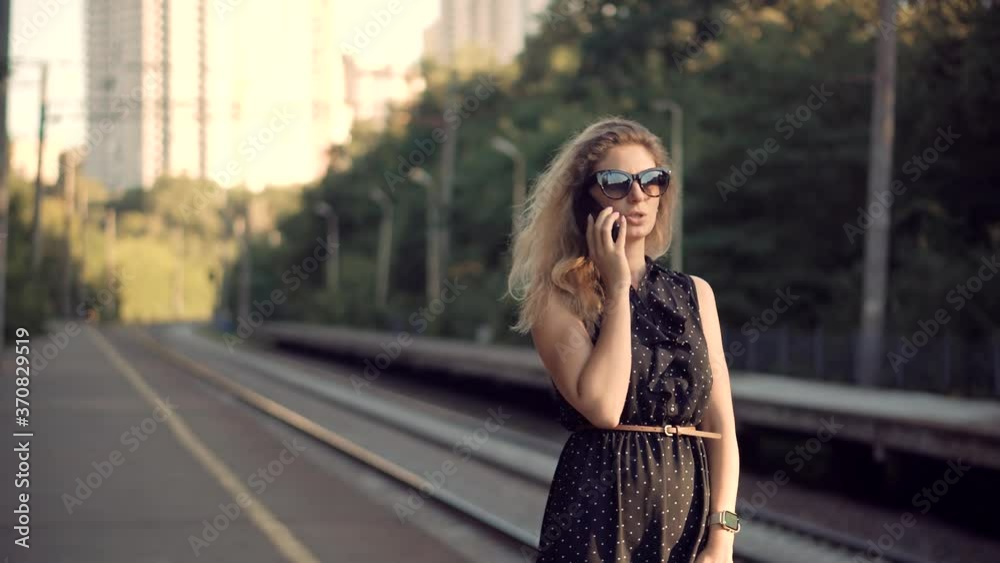 Woman Talking On Mobile Phone And Waiting Public Transport On Train Station.Active Lifestyle On Vacation Travel Tourism Adventure.Girl Call Friend On Smartphone And Looking At Watch On Train Platform. Woman Talking On Mobile Phone And Waiting Public Transport On Train Station.Active Lifestyle On Vacation Travel Tourism Adventure.Girl Call Friend On Smartphone And Looking At Watch On Train Platform.