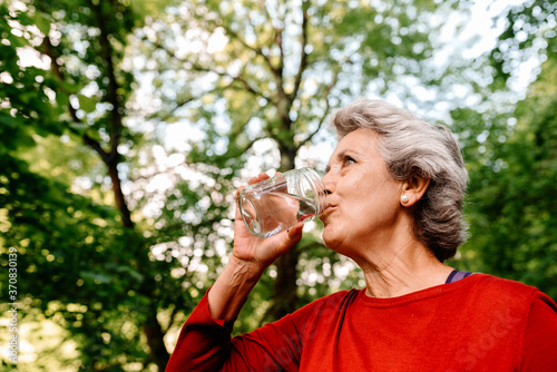 Crop elderly woman drinking water on nature photo