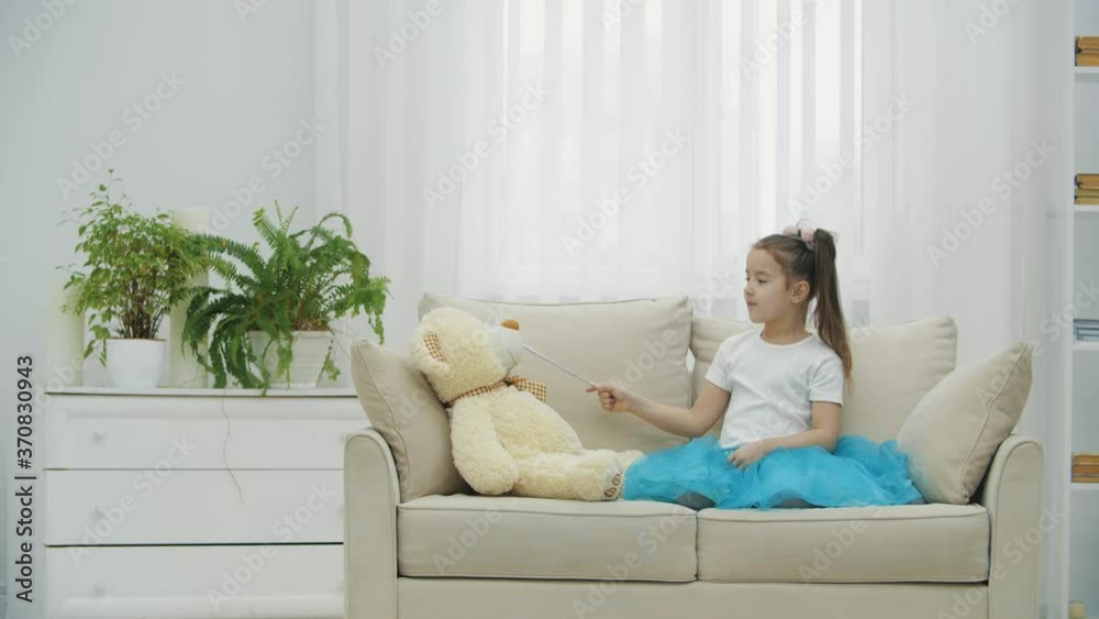 Little fairy sitting on the sofa with magic wand in her hand, conjuring her teddy bear, then directing the wand at the camera. Little fairy sitting on the sofa with magic wand in her hand, conjuring her teddy bear, then directing the wand at the camera.
