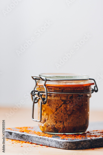 Side view of red pesto inside a glass jar against a neutral background