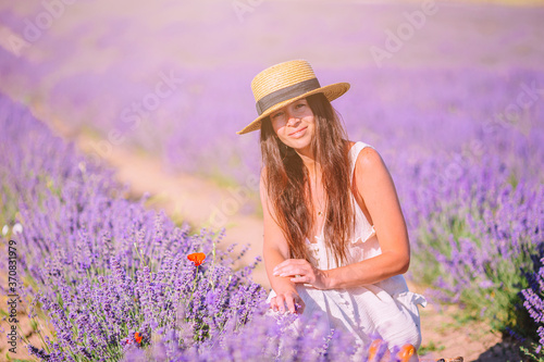 Woman in lavender flowers field in white dress and hat
