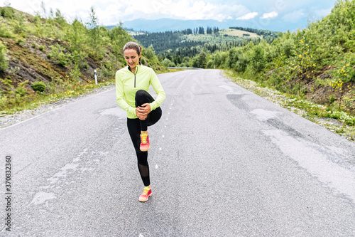 A girl is warming up her legs before running outdoors