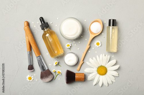 Flat lay composition with chamomiles, beauty accessories and cosmetic products on grey background
