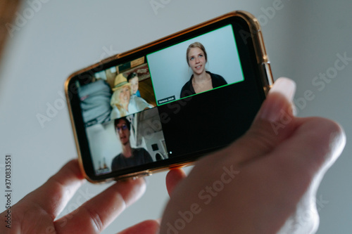 Crop anonymous female with manicured hands using mobile phone to answer video conference call with natives during social distancing
