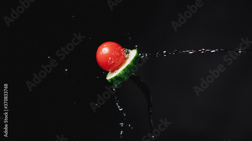 Tomato and Cucumber on a fork. Freeze motion splash water