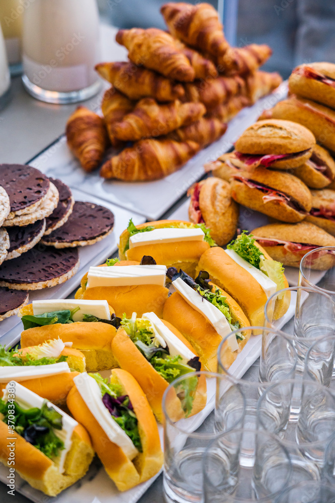 Tasty sandwiches with slices of bacon and sweet croissants served on plates for home party Tasty sandwiches with slices of bacon and sweet croissants served on plates for home party
