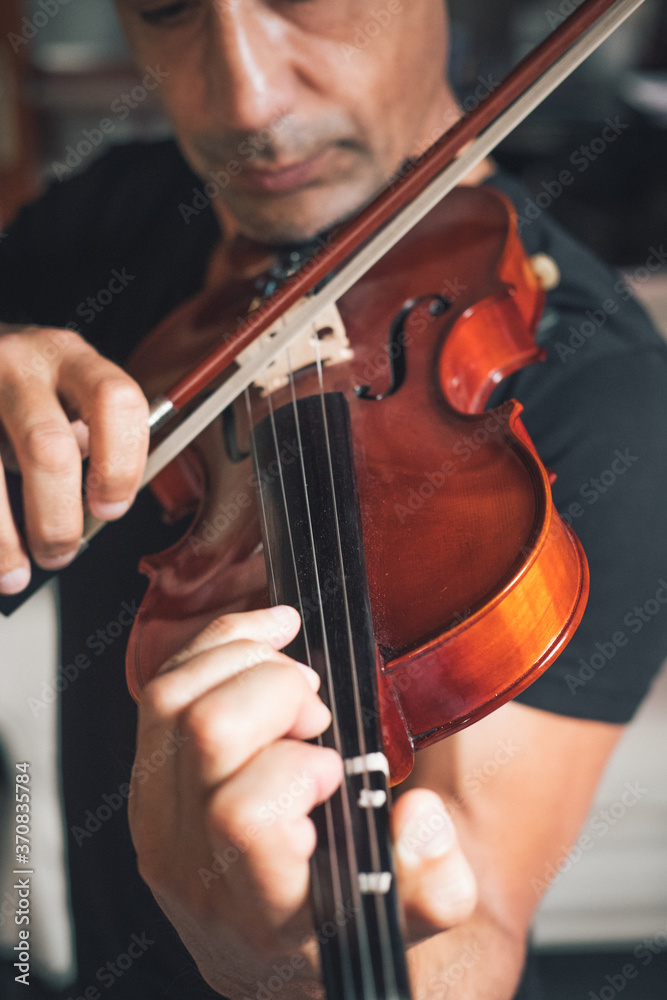 Cropped unrecognizable talented focused Hispanic male violinist playing violin during rehearsal Cropped unrecognizable talented focused Hispanic male violinist playing violin during rehearsal