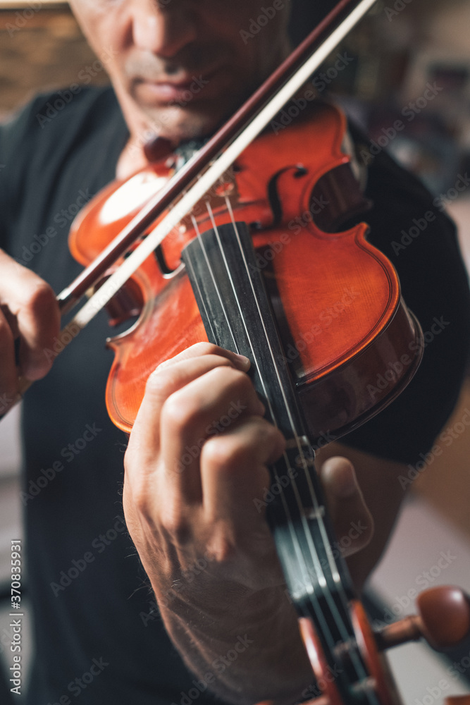 Cropped unrecognizable talented focused Hispanic male violinist playing violin during rehearsal Cropped unrecognizable talented focused Hispanic male violinist playing violin during rehearsal