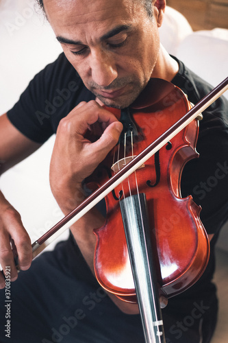 From above talented focused Hispanic male violinist playing violin during rehearsal