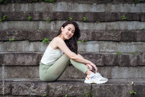 Positive ethnic woman sitting on shabby stairs in park photo