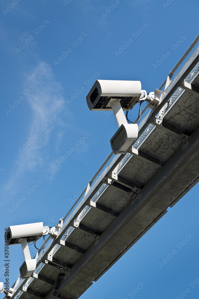 From below of road security camera recording speed of automobile driving along highway on sunny day with blue sky From below of road security camera recording speed of automobile driving along highway on sunny day with blue sky
