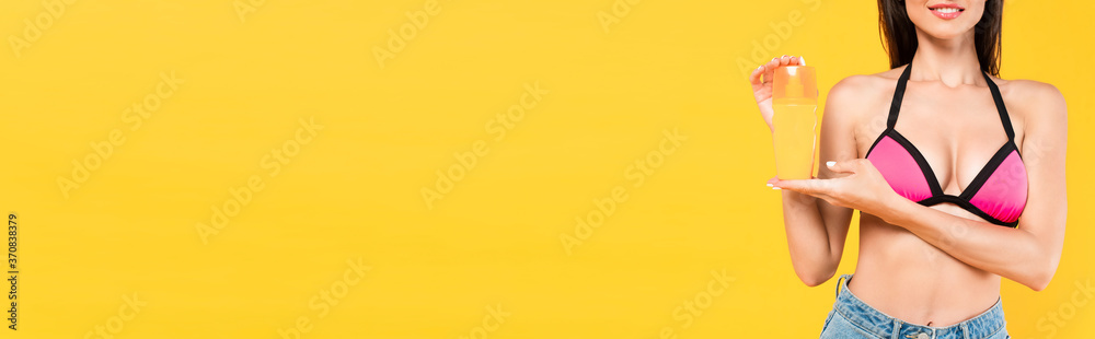 Φωτογραφία horizontal crop of happy girl in swimsuit holding bottle with suntan isolated on