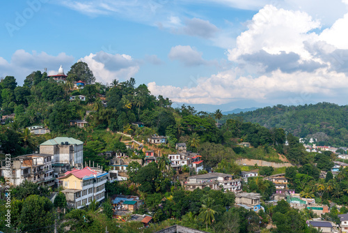 Amazing cityscape of colorful residential buildings located on green hill against blue sky in Kandi photo