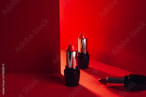 Set of bright red lipsticks in elegant shiny tubes placed on red background photo