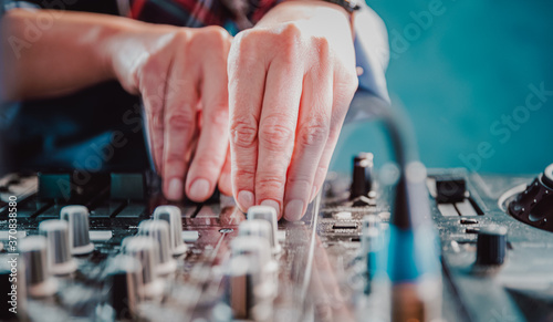 DJ Hands creating and regulating music on dj console mixer in concert nightclub stage.