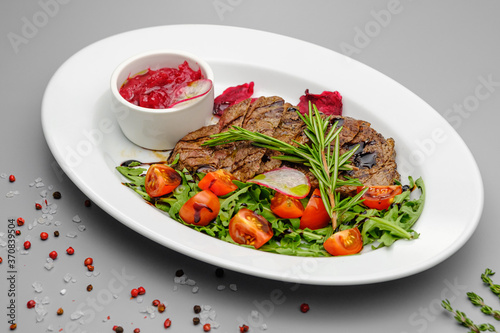 Grilled maso with vegetables and rosemary on a white plate.