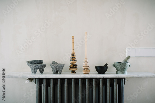 Various kitchen utensils including mortars with pestles arranged in row on marble counter near wall photo