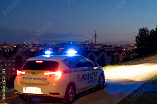 Contemporary police vehicle with siren light on the road on background of amazing night cityscape