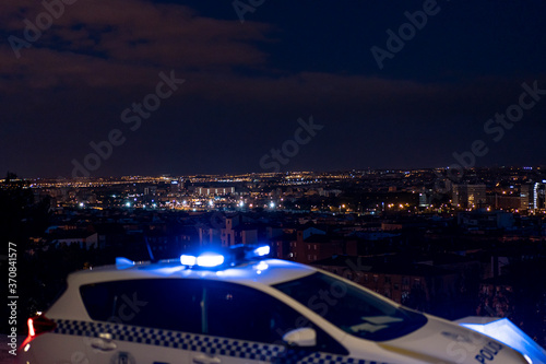 Contemporary police vehicle with siren light parked on asphalt road on background of amazing night cityscape