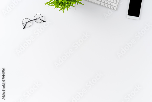 Office desktop concept with computer keyboard  phone  eyeglasses and small flower on white background. Top view