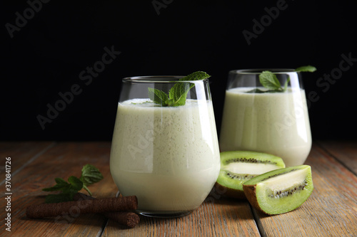 Tasty milk shake with kiwi on wooden table