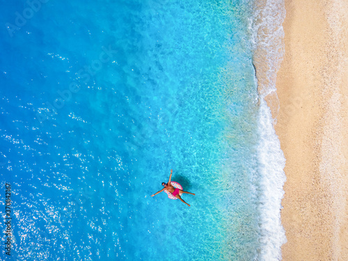 Ein Mann treibt auf einem aufblasbarem Donut über türkisem Meer und genießt den Sommer Urlaub am Strand © moofushi