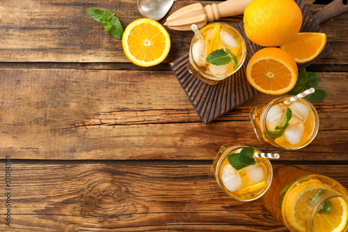 Delicious refreshing drink with orange slices on wooden table, flat lay. Space for text