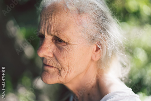 Portrait of a gray-haired adult grandmother against the background of nature