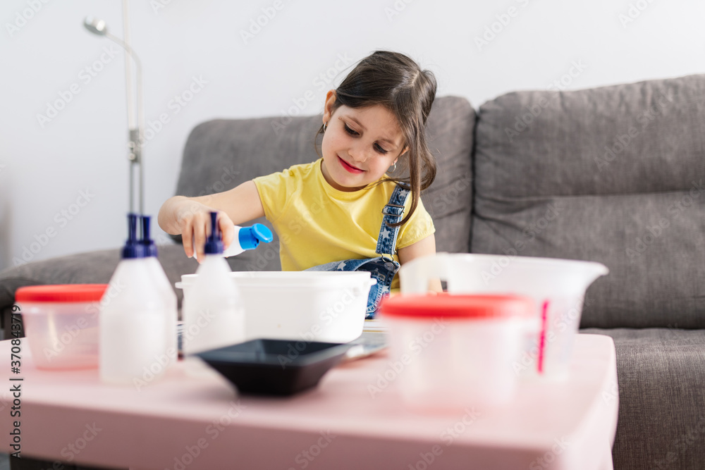 Cheerful kid with dirty face in casual wear pouring a blend while sitting on comfortable couch in apartment in sunlight