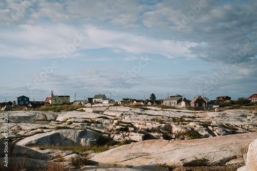 Lovely cottages located in stony terrain against cloudy sky on dull day in Peggys Cove, Canada photo