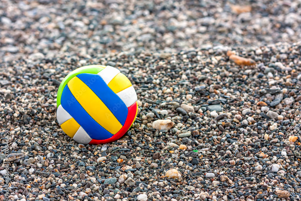 Close up of colored child's ball on a sea pebble beach. Summer beach games and childhood concept.