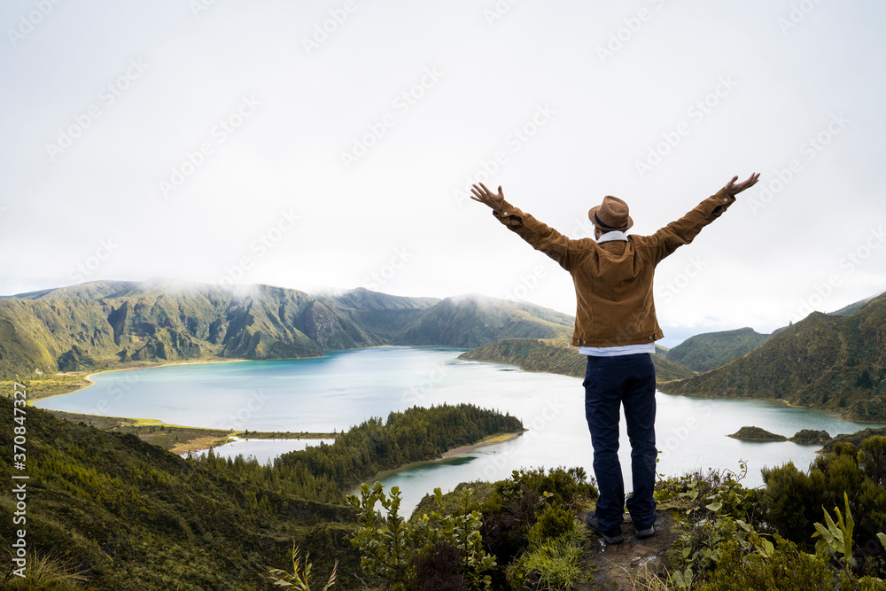 Rear view of explorer with arms raised enjoying view at scenic Sao Miguel Island in Azores, Portugal Rear view of explorer with arms raised enjoying view at scenic Sao Miguel Island in Azores, Portugal