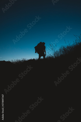 Silhouette of backpacker hiking under the moonlight