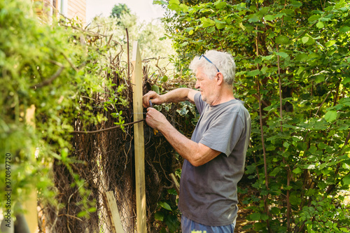 Senior man fixing garden fence photo