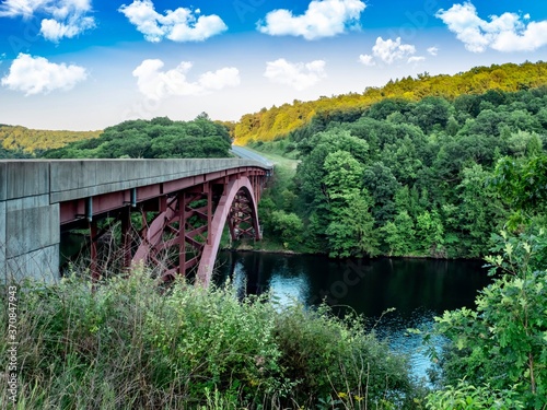 Bridge going over the Clarion River near Clarion, Pennsylvania, not far from the Allegheny National Forest.  Green Trees, Bridge over the river and bright blue cloud filled sky in the background. photo