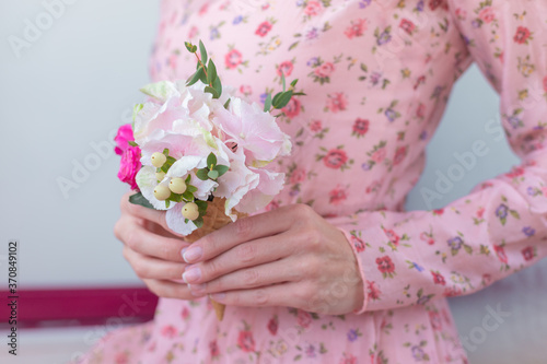 Women in vintage dress holding ice cream waffle cone with pink roses and hydrangea .Floral composition of beautiful spring fresh flowers isolated indoor. Florist at work.Copy Space.Food photo. © Iryna