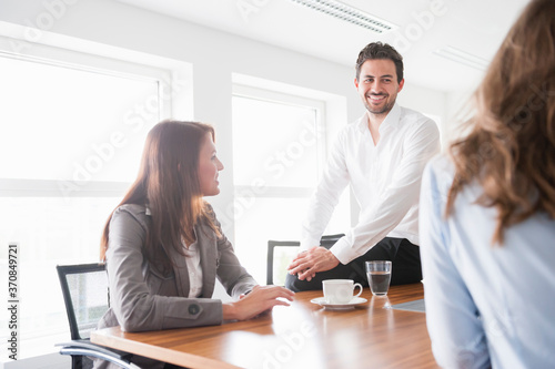 Happy business colleagues discussing in brightly lit board room