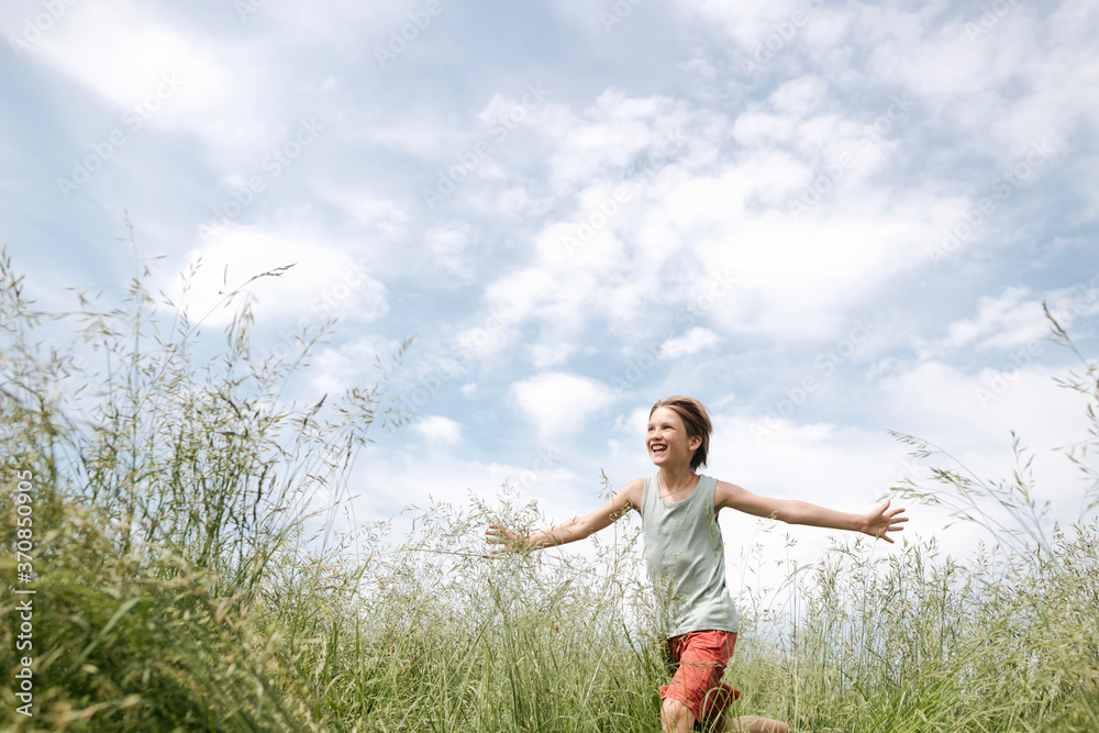 Portrait of happy boy running on a field with arms outstretched Portrait of happy boy running on a field with arms outstretched